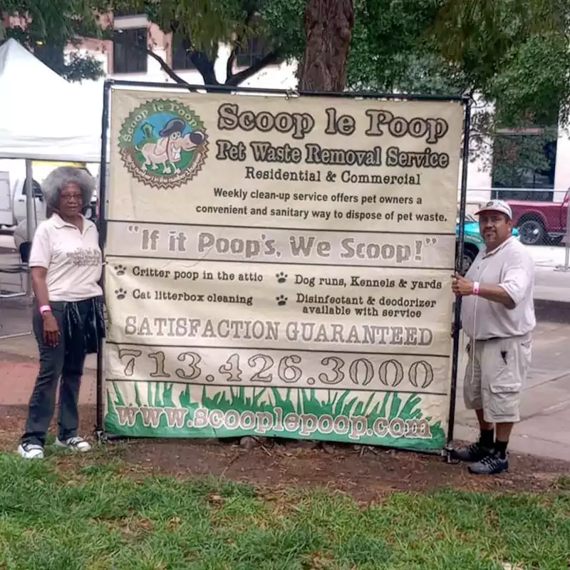 Two Scoop le Poop employees holding up our large banner at the annual Houston Humane Society Fun Run.