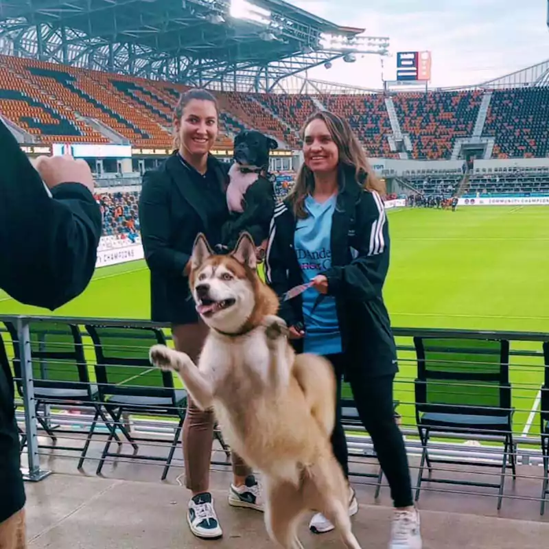 Two women with their dogs at the annual Houston Dash Pups on the Pitch event.
