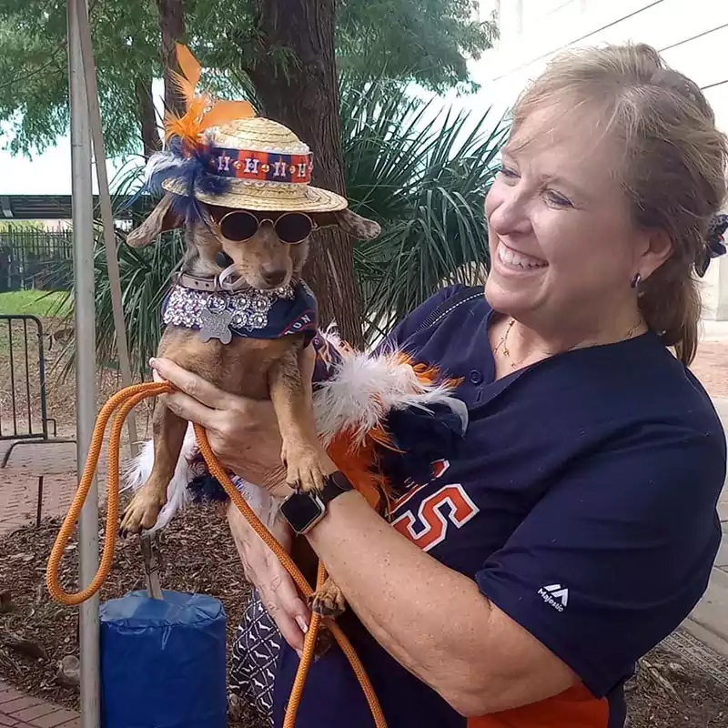 Patron with her small dog dressed up in team colors at the annual Astros Dog Days event.